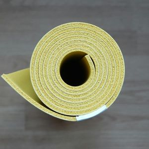 A yoga mat rolled up on a wooden floor.