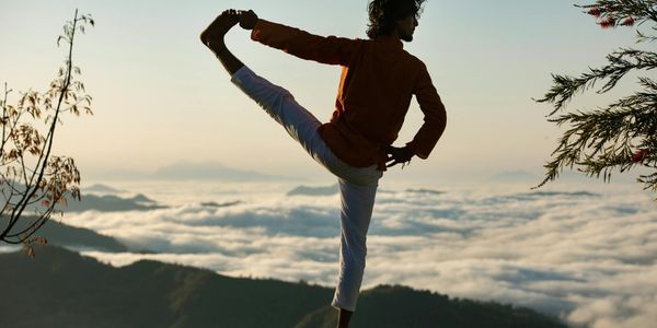 Silhouette of a person in a balancing yoga pose at sunrise.