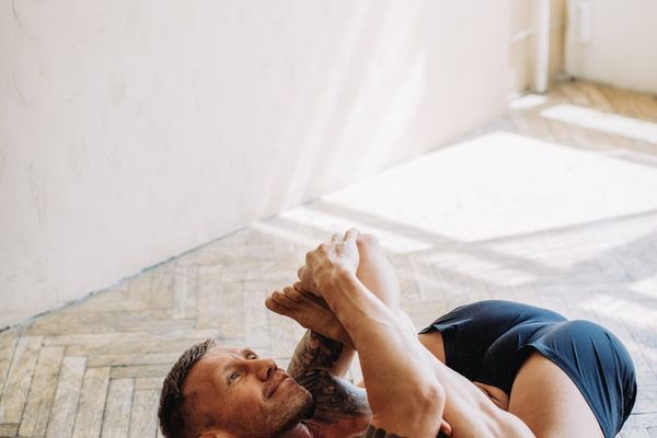 Woman in a calm, focused yoga pose in a bright, minimalist room.